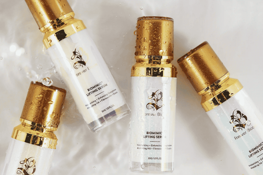 Four bottles of Forever Bloom Serum, photographed from above with droplets of water.