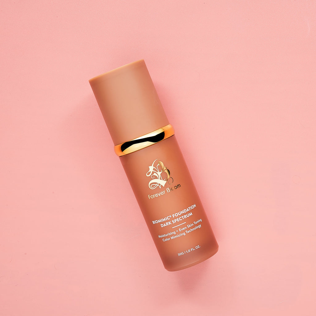 dark shade color changing foundation bottle with a gold cap on a pink background