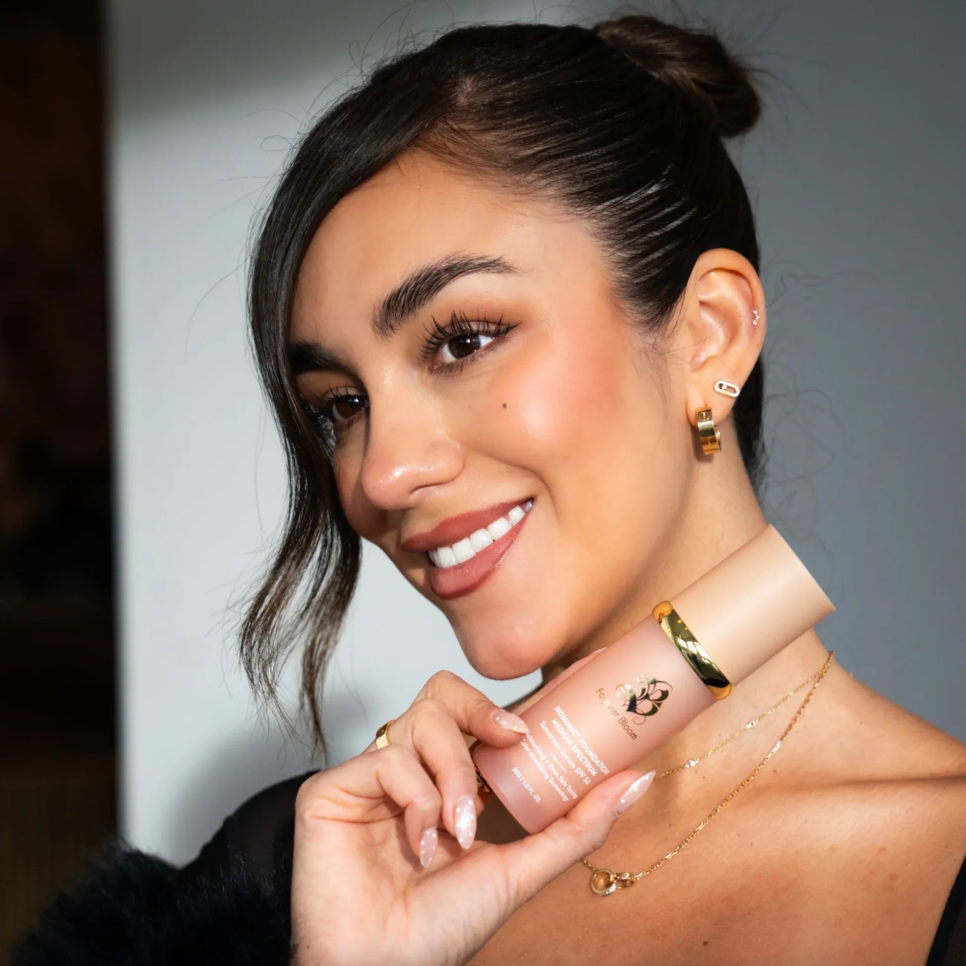 Woman holding a skincare product with a neutral background