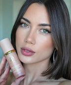 Woman holding a biomimc foundation medium product perfect match for her skin with a neutral background