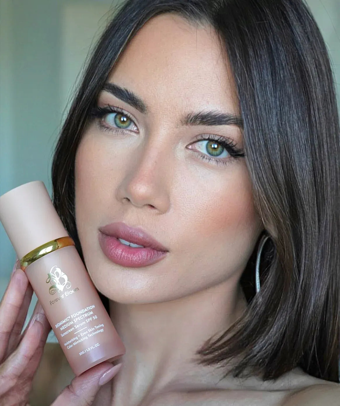 Woman holding a biomimc foundation medium product perfect match for her skin with a neutral background